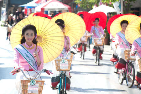 Group of Pretty woman in traditional dresses ride a bicycle parade show in Umbrella Festival .のeditorial素材