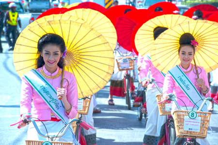 Group of Pretty woman in traditional dresses ride a bicycle parade show in Umbrella Festival .のeditorial素材