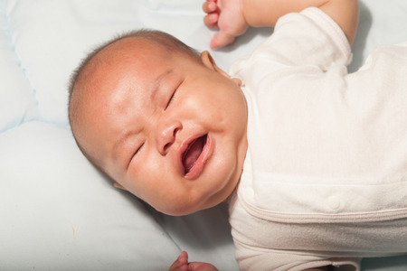 Newborn Asian baby girl lying and crying on a bed.の写真素材
