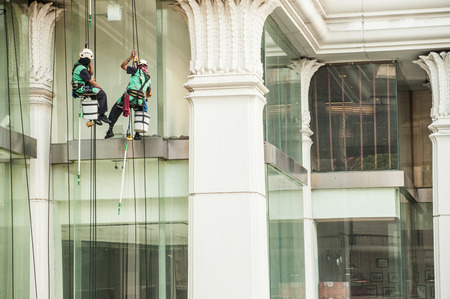 Glass cleaner abseiling from a tall building. Window cleaners at work on skyscraper,Bangkok,Thailand.のeditorial素材
