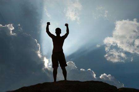 Positive male holding hand up and expressing gladness while standing on stone.の写真素材