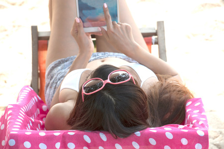 Pretty Asian woman relax on a bed with tablet.の写真素材