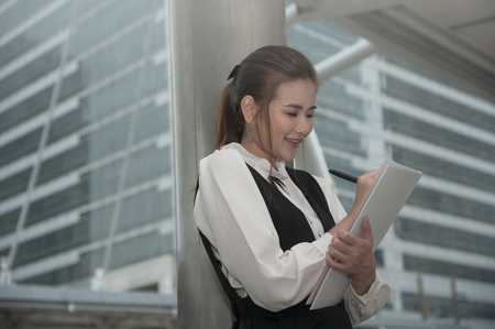 Asian Pretty woman in black dress writing document stand on crossing bridge landmark of Bangkok.の写真素材