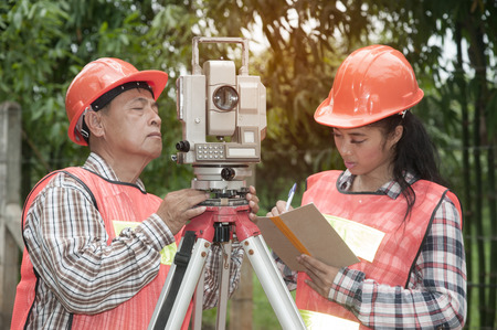 Surveyor or Engineer making measure by Theodolite with partner in a field.の写真素材