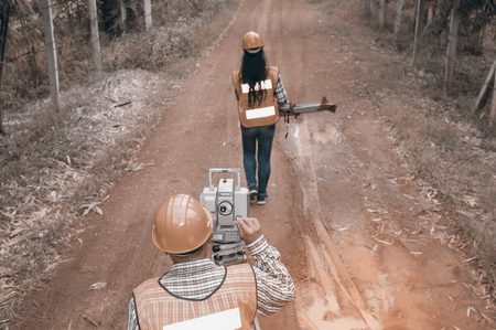 Surveyor or Engineer making measure by Theodolite with partner on the street in a field.の写真素材