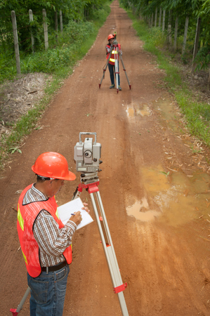 Surveyor or Engineer making measure by Theodolite with partner on the street in a field.の写真素材