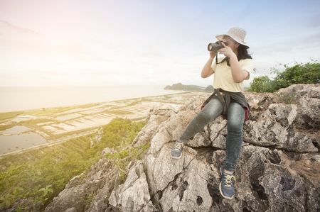 Young Asian traveler woman take a photo in happiness of sitting on top view point.の写真素材