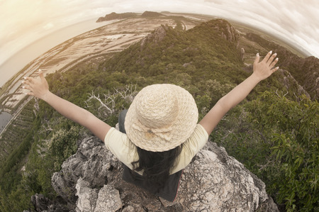 Funny female traveler with hat sitting on top of a mountain and enjoying , freedom viewpoint of Thailand.の写真素材