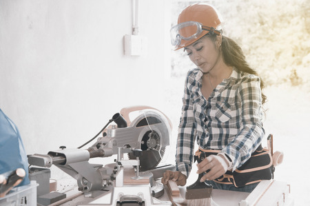 Pretty Asian carpenter woman is marking on wood for cut.の写真素材