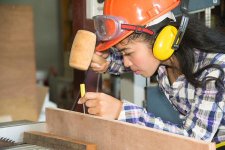 Asian pretty female carpenter using wood hammer for wood.の写真素材