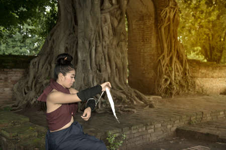 Pretty Asian woman posing in Thai ancient warriors at Gate of time of Wat Phra Ngam in Ayutthaya Historical Park ,Thailand.の写真素材