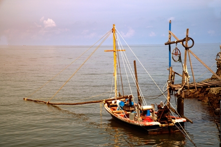 Fishing boat on the sea near wooden bridge.の写真素材