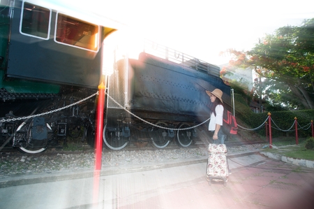 Pretty Asian Women backpacker with luggage standing and posing at Steam locomotive.