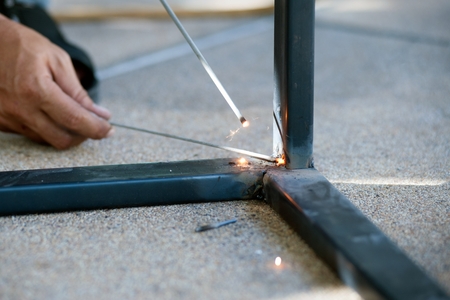 The worker is welding sparks table steel in factory.