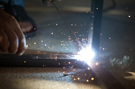The worker is welding sparks table steel in factory.