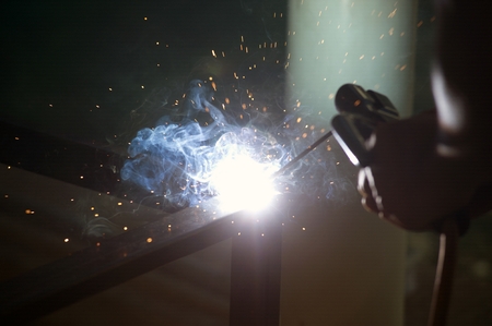 The worker is welding sparks table steel in factory.