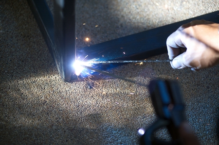 The worker is welding sparks table steel in factory.