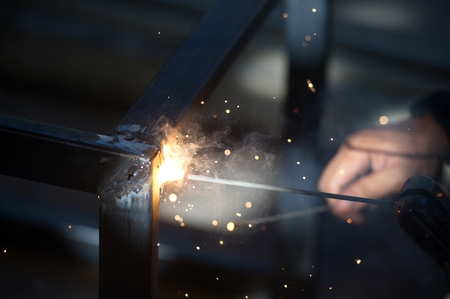 The worker is welding sparks table steel in factory.