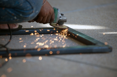 The worker is welding metal part of table steel in factory.の写真素材