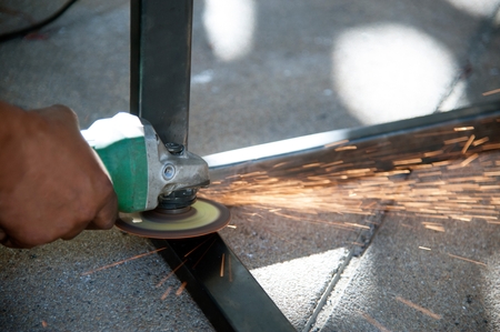 The worker is welding metal part of table steel in factory.