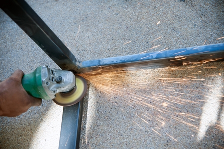 The worker is welding metal part of table steel in factory.