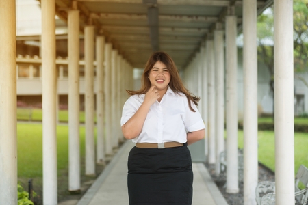Asian pretty smiley face fat woman pose in student uniform on walkway.の写真素材