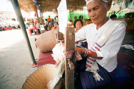 PHAYAO,THAILAND-MAY 9,2015 : Unidentified senior Tai Lue minority woman is a spinning traditional cotton yarn treads by ancient rolling machine made of wood showing in 8th Ethnic amazing festival.のeditorial素材