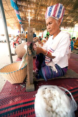 PHAYAO,THAILAND-MAY 9,2015 : Unidentified senior Tai Lue minority woman is a spinning traditional cotton yarn treads by ancient rolling machine made of wood showing in 8th Ethnic amazing festival.のeditorial素材