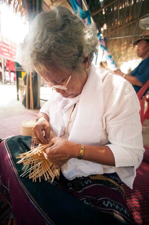 PHAYAO, THAILAND - MAY 9, 2015 : Unidentified senior Tai Lue minority woman made a tradition woven bamboo container for steamed cooked glutinous rice with her hand showing in 8th Ethnic amazing festival.のeditorial素材