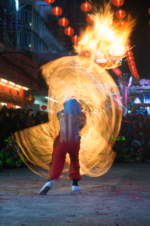 NAKORN SAWAN , THAILAND - FEBRUARY 18, 2018 : Unidentified fighter of warriors  ( Aung-Gor )  the fire swinging with long rope on street in parade during Chinese New Year festival in Nakorn Sawan Province , Middle of Thailand.のeditorial素材