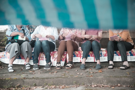 Row of legs woman sitting in a park.の写真素材