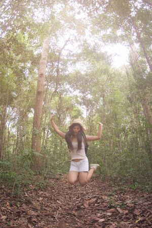Pretty Asian woman jumping fun and happiness in the forest.の写真素材
