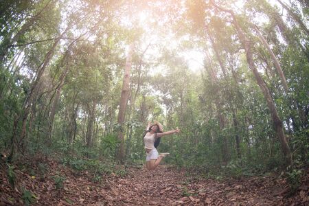 Pretty Asian woman jumping fun and happiness in the forest.の写真素材