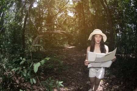 Pretty Asian woman looking a map in the forest.の写真素材