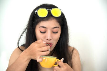 Portrait of Asian dark-haired woman drinking coffee against on white background.