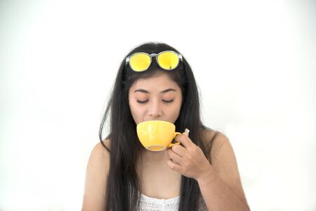 Portrait of Asian dark-haired woman drinking coffee against on white background.の写真素材
