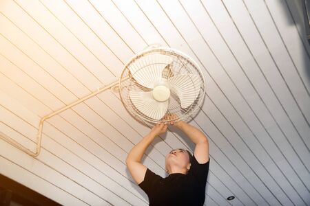 The housekeeper is installing the ceiling fan after being cleaned.の写真素材