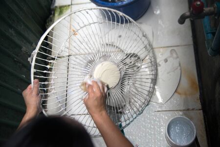Housewife use white cloth Wipe and clean the electric fan.の写真素材