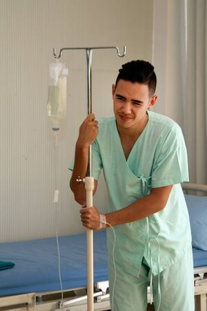 The male patient had stomach ache and was walking inside the room using saline pillar as an anchor. And undergoing treatment in a room at hospital.の写真素材