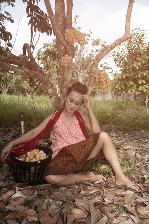 The senior Asian woman pose is sitting relaxation under longkong tree in the garden with happiness.の写真素材
