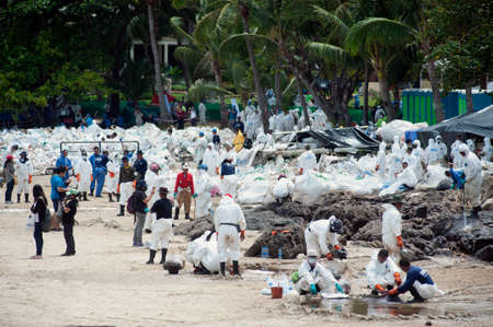 RAYONG,THAILAND-FEBRUARY 8,2013 : Unidentified Workers and volunteers are shoveling sand with crude oil contaminated on the beach in a large plastic bag at Prew beach , Samet island on Khao Laem Ya - Ko Samet National Park in Thailand.のeditorial素材
