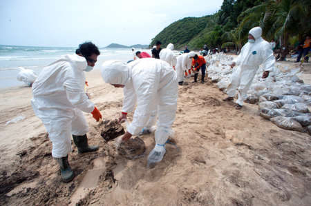 RAYONG,THAILAND-FEBRUARY 8,2013 : Unidentified Workers and volunteers are shoveling sand with crude oil contaminated on the beach in a large plastic bag at Prew beach , Samet island on Khao Laem Ya - Ko Samet National Park in Thailand.のeditorial素材
