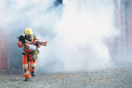 The firefighter was helping the girl. Leave the burning and smoky building.の写真素材
