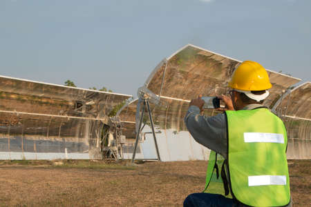 Uniformed and helmeted officers inspect and photograph parabolic solar rails using their mobile...