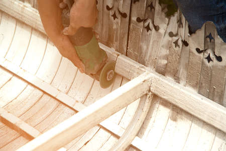 A male worker is cutting a metal awning laid on the floor with a cutting machine.の写真素材