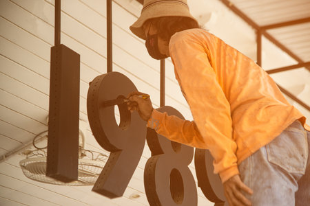 Male worker paints black numbers of shop with paint brushes.の写真素材