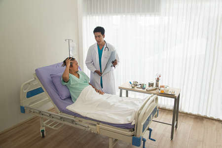 A Asian male doctor holds a brain X-ray film where CT scans and analyzes the results while...