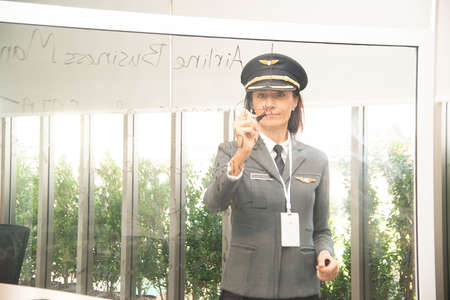 The senior woman in flying uniform standing at chalk board To explain to the coworkers how to work.の写真素材