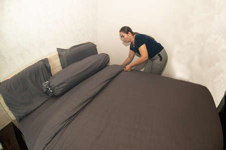 Asian female  maid making bed in hotel room. Housekeeper Making Bed.