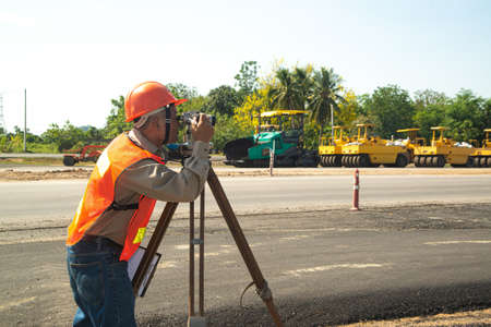 Engineer or surveyor working with theodolite equipment at road construction site.の写真素材